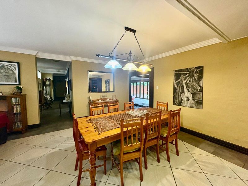 A dining room featuring tiled flooring, cove cornicing, and a central pendant light fixture, providing a functional space for family meals.