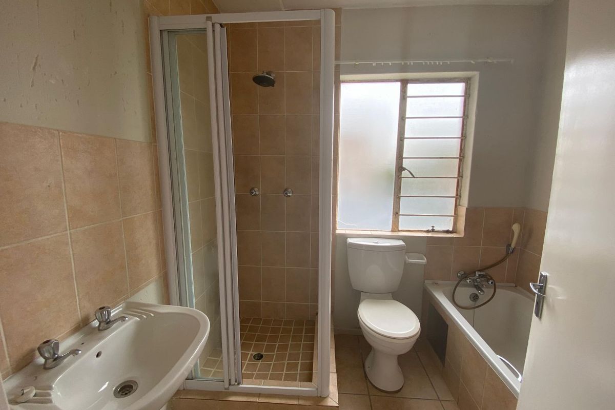 A dated bathroom featuring a separate shower cubicle, bathtub, pedestal basin, and toilet with tiled walls and flooring.