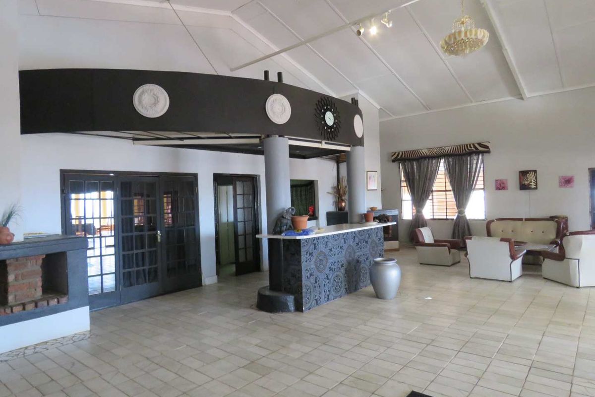Spacious lodge reception area featuring a central service counter, vaulted ceilings, tiled flooring, and multiple access points to adjoining rooms.