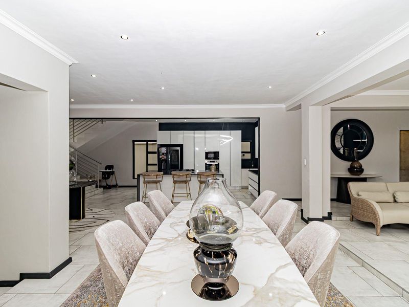 Spacious open-plan dining and kitchen area featuring modern tiled floors, recessed lighting, and a sleek kitchen island with contemporary cabinetry.