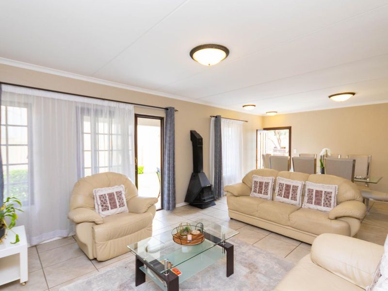 Spacious open-plan living and dining area featuring tiled flooring, a freestanding fireplace, and multiple sliding glass doors providing access to the outdoor space.