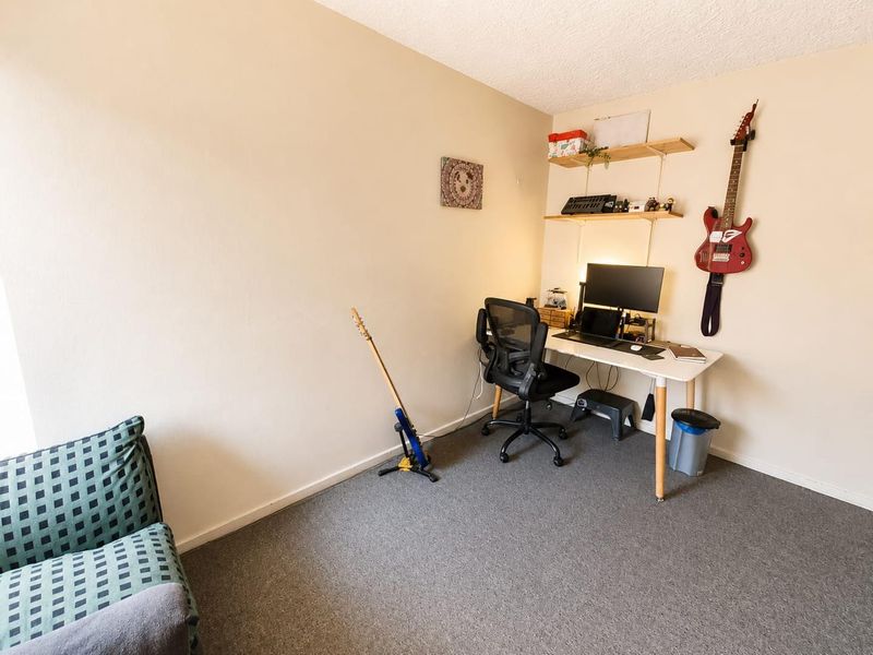 A functional home office space featuring wall-mounted shelving and neutral carpeting, suitable for a dedicated workspace or study area.