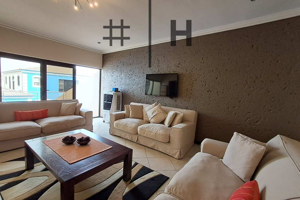 Spacious living room featuring a textured accent wall, tiled flooring, and large sliding glass doors leading to an outdoor area.