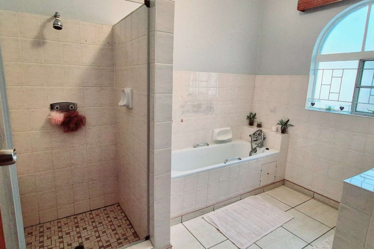A functional bathroom featuring a separate shower enclosure, a built-in bathtub, and a vanity basin with tiled finishes.