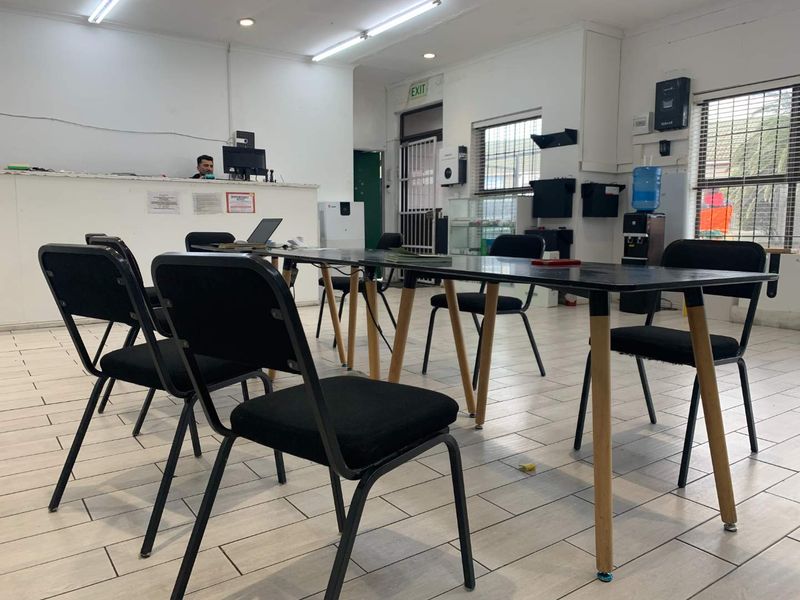 A functional office space featuring tiled flooring, a reception counter, and security access points, suitable for commercial or administrative use.