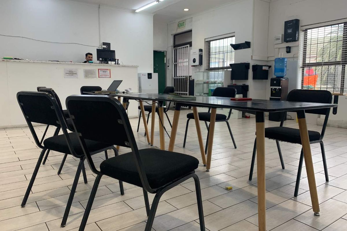 A functional office space featuring tiled flooring, a reception counter, and security access points, suitable for commercial or administrative use.