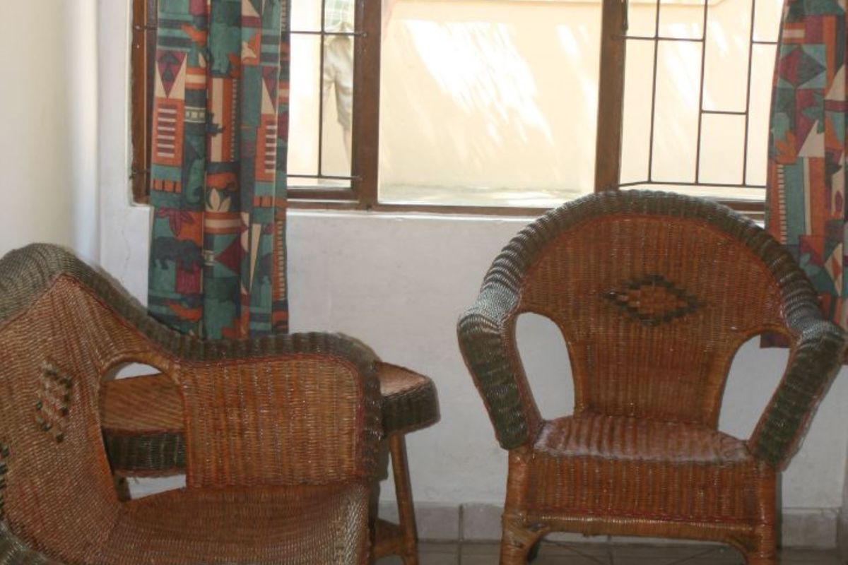 A simple interior space featuring tiled flooring and a large window with security bars, providing natural light and a view of the exterior.