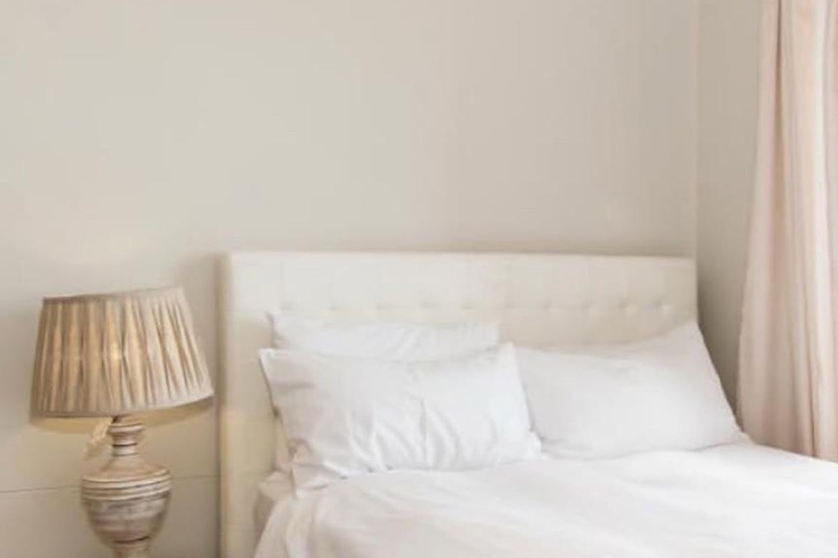 A neutrally decorated bedroom featuring crown molding and soft window treatments, providing a clean and comfortable sleeping space.