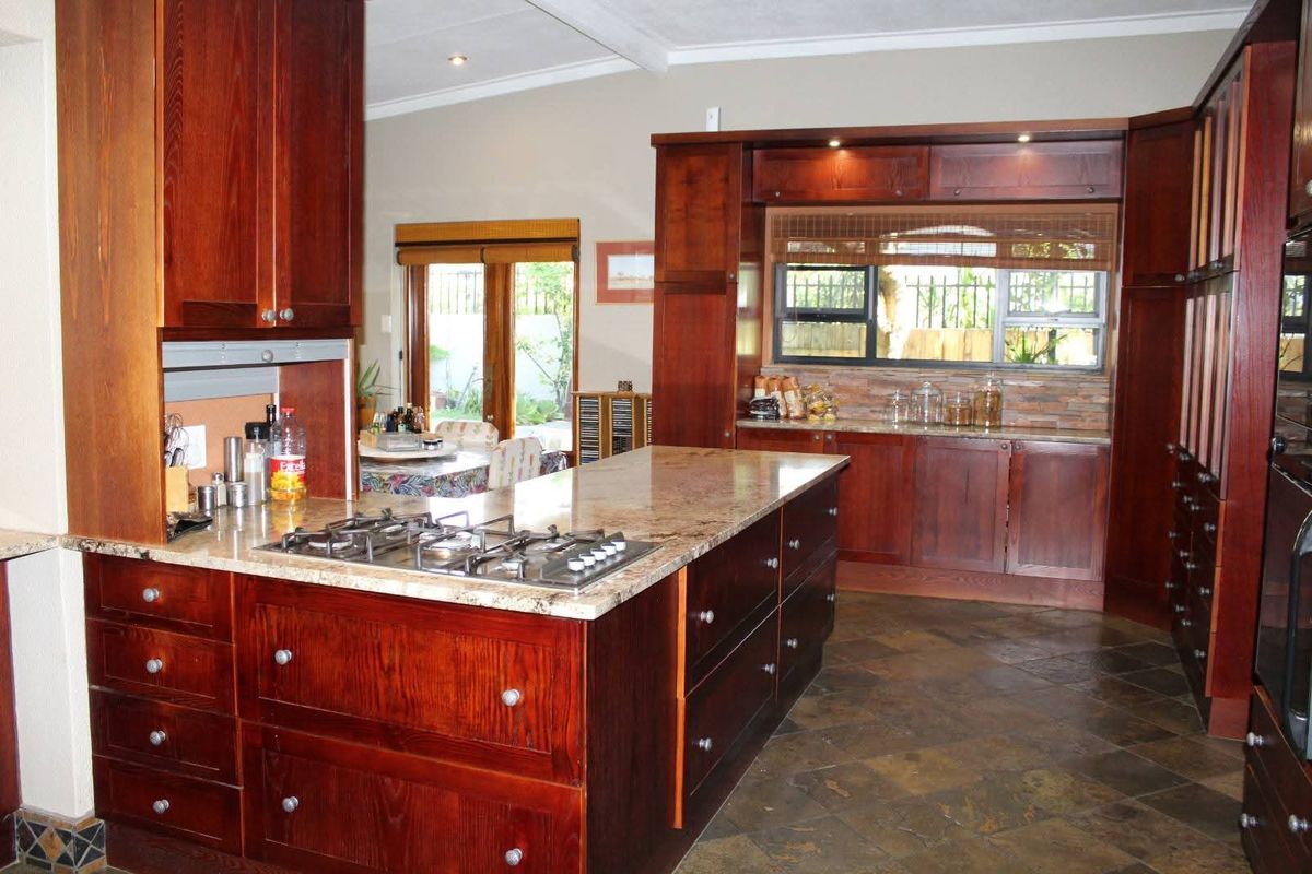 Spacious kitchen featuring dark wood cabinetry, granite countertops, a central island with a built-in gas hob, and slate tile flooring.