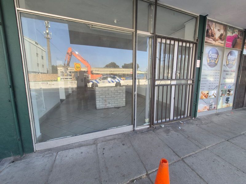 Front exterior view of a commercial storefront featuring large glass windows, a metal security gate, and tiled flooring, currently vacant.