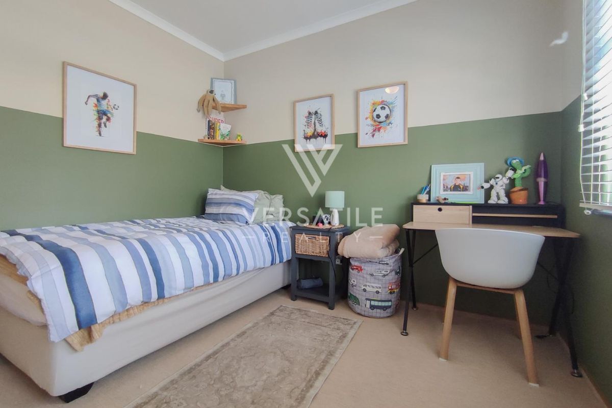 A well-maintained bedroom featuring two-tone painted walls, neutral carpeting, and venetian blinds, providing a comfortable and functional living space.