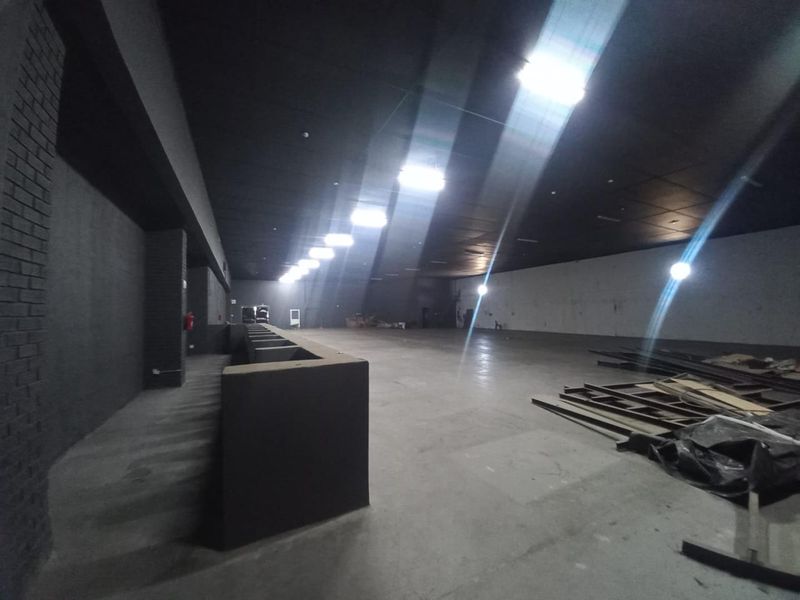 A large, open-plan industrial utility space featuring concrete flooring, dark-toned walls, and recessed ceiling lighting, suitable for various commercial or storage applications.