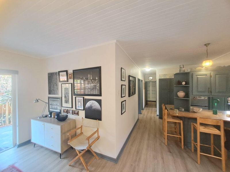 Open plan living area featuring timber-look flooring, tongue and groove ceiling, and a functional kitchen with a breakfast bar and integrated cabinetry.