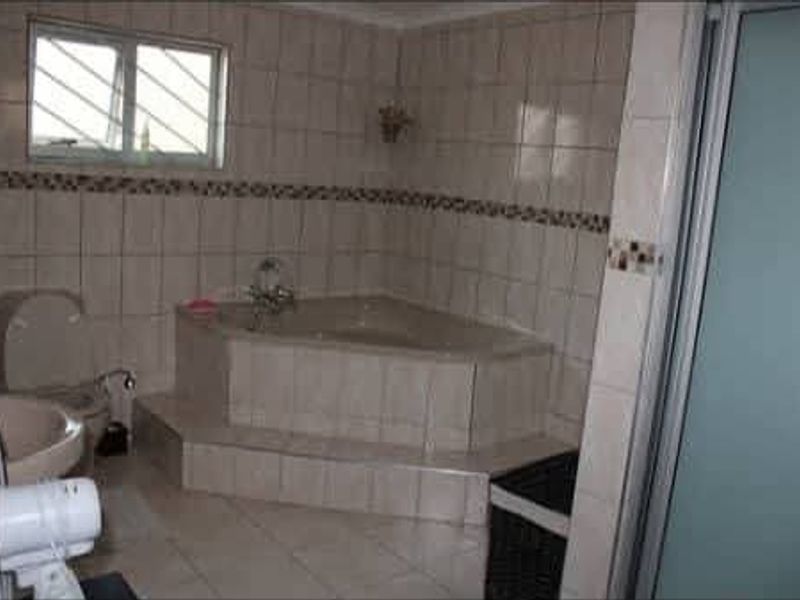 A dated bathroom featuring a corner bathtub, tiled walls and flooring, and a separate shower enclosure.