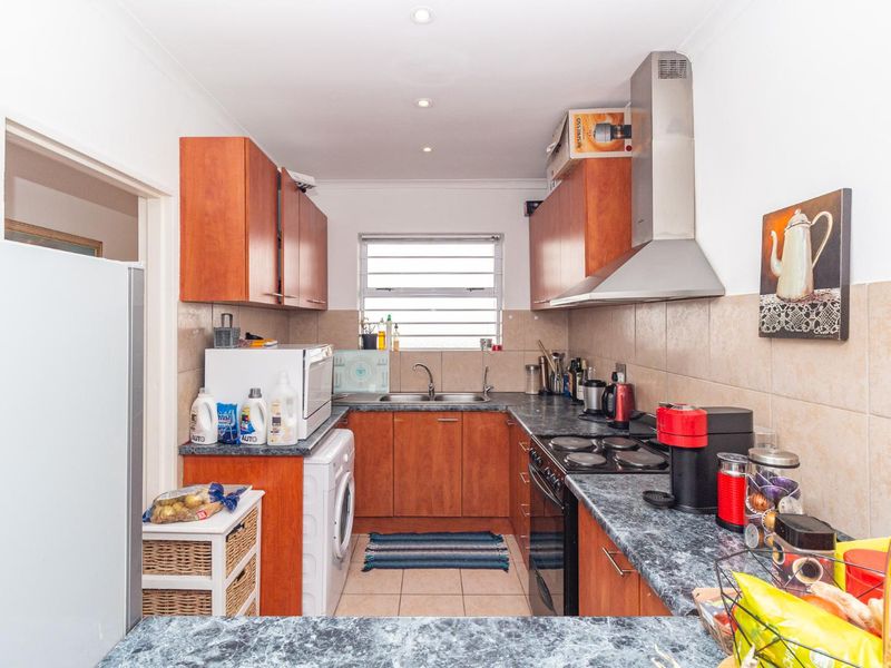 Functional kitchen featuring wood-finish cabinetry, laminate countertops, a built-in oven with extractor fan, and a tiled backsplash.