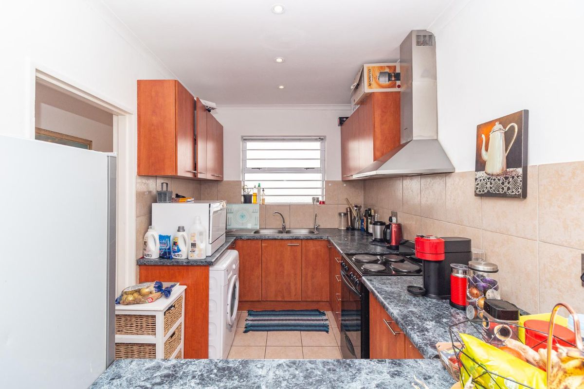 Functional kitchen featuring wood-finish cabinetry, laminate countertops, a built-in oven with extractor fan, and a tiled backsplash.