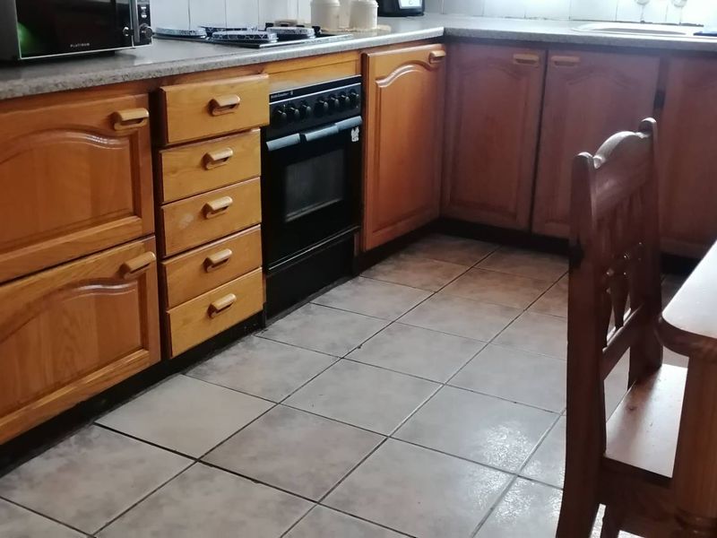 A functional kitchen featuring wooden cabinetry, a built-in oven, laminate countertops, and tiled flooring, offering a traditional layout with ample storage space.