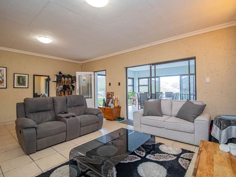 Spacious living room featuring tiled flooring, cove cornicing, and large sliding glass doors providing access to an adjoining patio area.