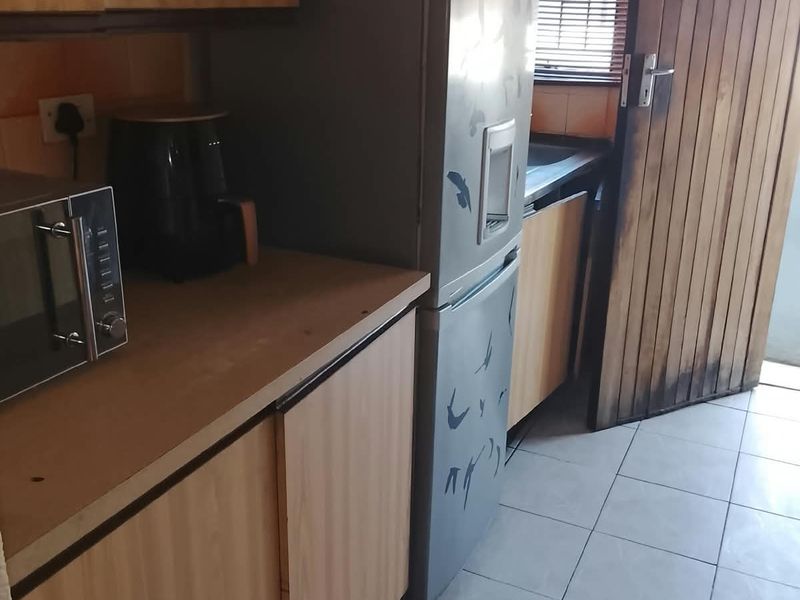 A functional scullery area featuring laminate cabinetry, tiled flooring, and a timber door, providing additional prep and storage space.