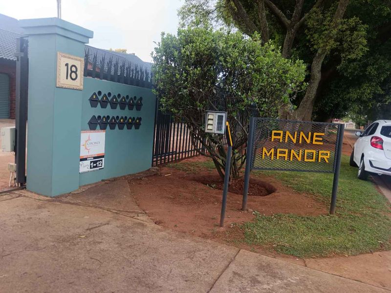Entrance view of Anne Manor complex featuring security gate, intercom system, and designated post boxes for residents.
