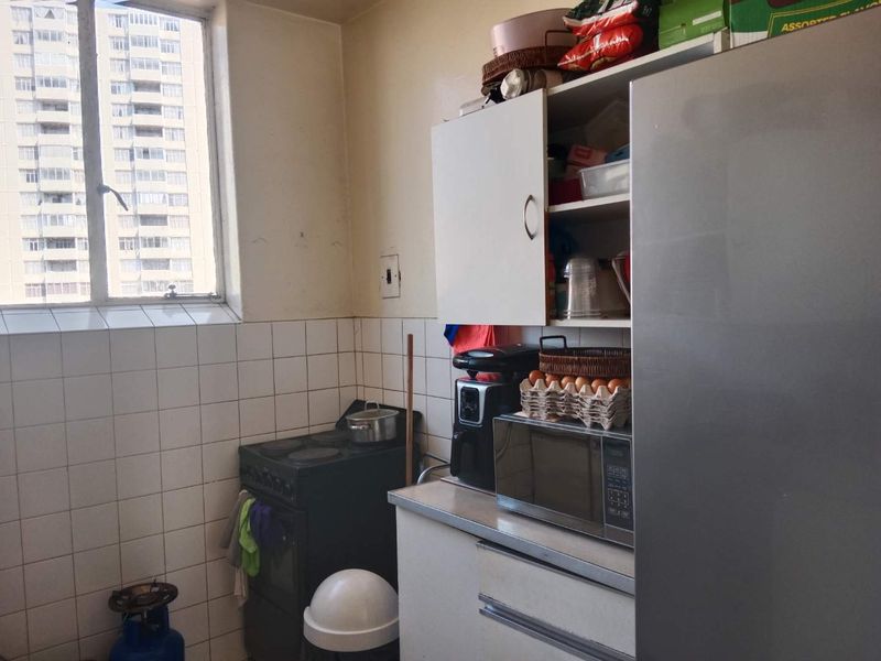 A compact kitchen featuring tiled splashbacks, built-in cabinetry, and a freestanding stove, offering a functional layout with natural light from the window.