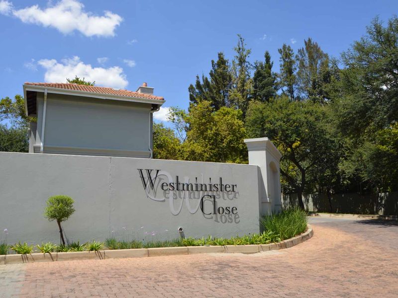 The entrance to Westminister Close, featuring a well-maintained boundary wall, paved driveway, and established landscaping.
