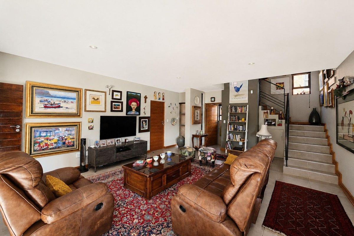 Spacious open-plan living area featuring tiled floors, recessed lighting, and a staircase with a modern metal railing leading to the upper level.