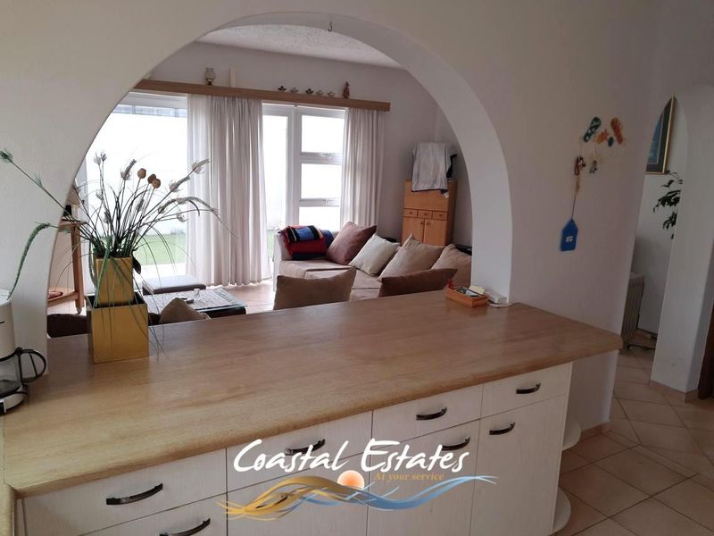 Open plan living area featuring a kitchen with wooden countertops and an arched transition leading to a bright lounge with sliding door access.