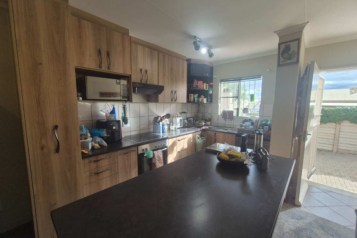 A functional kitchen featuring wood-look cabinetry, a central island, built-in oven and hob, and direct access to an outdoor area.