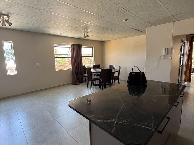 Open plan living and dining area featuring a kitchen island with stone countertop, tiled flooring, and a drop ceiling.