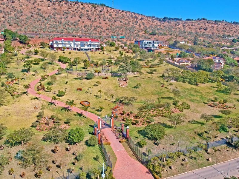 An aerial view of a large residential estate featuring extensive landscaped grounds, a paved driveway, and secure perimeter fencing.
