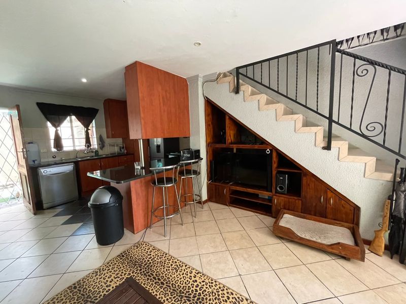 Open-plan living area featuring a kitchen with granite countertops and custom under-stair cabinetry with a wrought iron staircase railing.