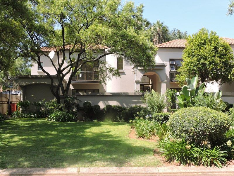 Front view of a two-story residential house featuring a landscaped garden, paved walkway, and balcony access.