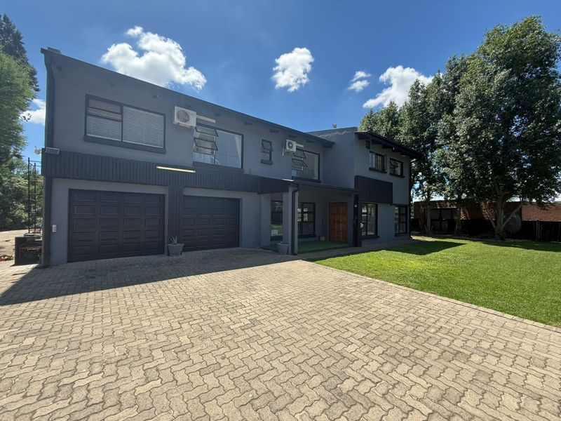 A modern two-story house featuring a paved driveway, double garage, and well-maintained front lawn.