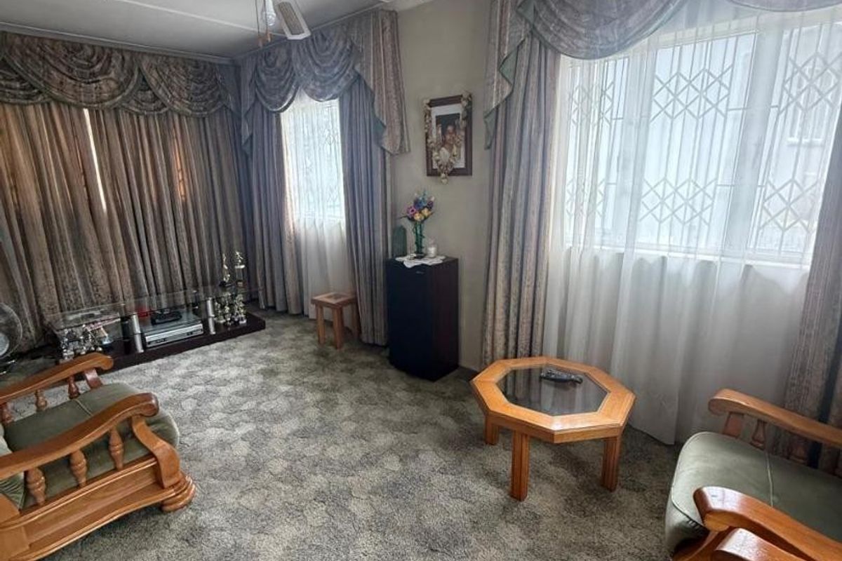 A living room featuring a ceiling fan and windows fitted with security bars, finished with wall-to-wall carpeting.