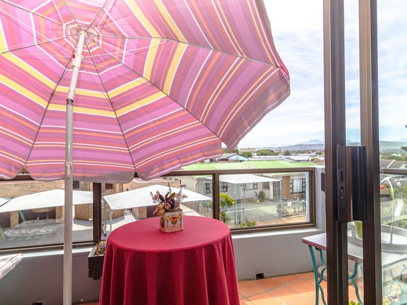 A balcony featuring tiled flooring and a glass balustrade, offering an elevated view of the surrounding neighborhood.