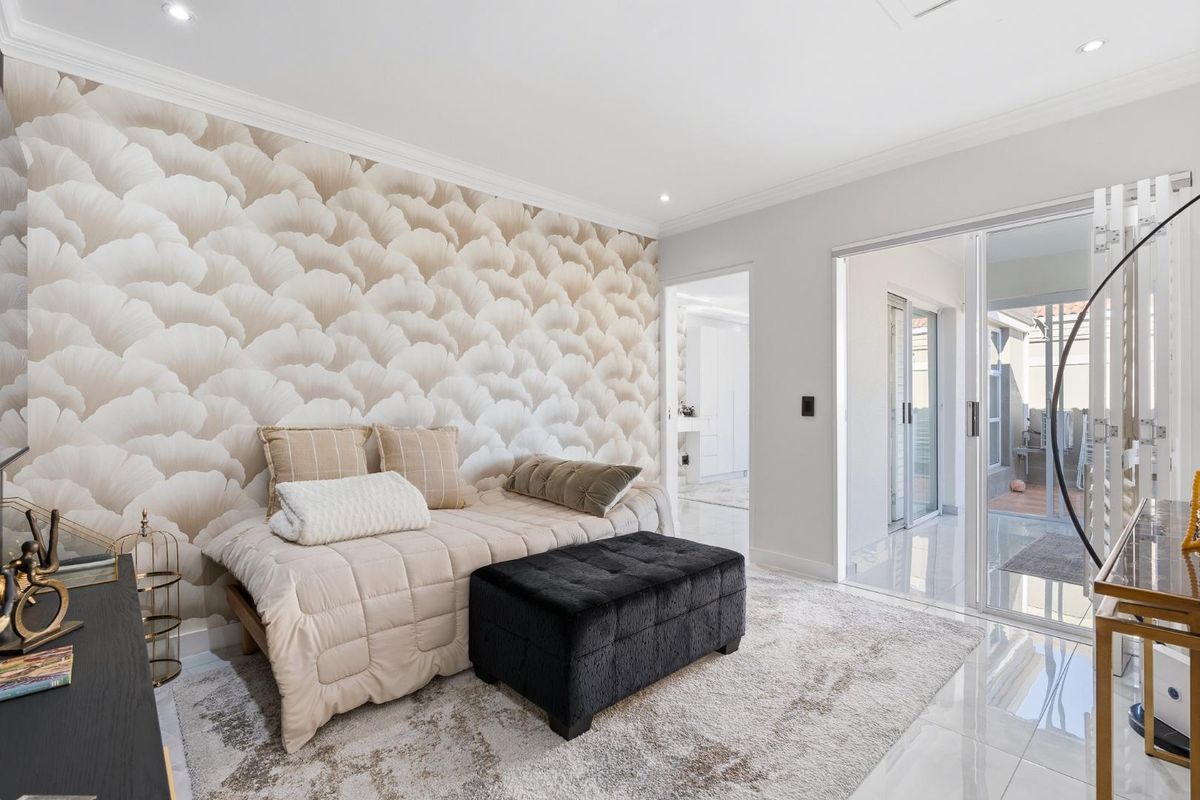 A bright bedroom featuring modern tiled flooring, recessed downlights, crown molding, and sliding glass doors providing access to an outdoor area.