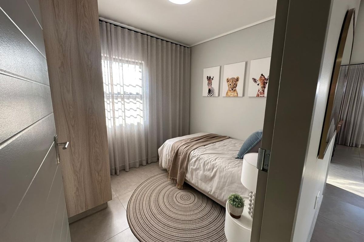 A well-maintained bedroom featuring neutral tiled flooring, a built-in wardrobe, and soft natural lighting through window curtains.