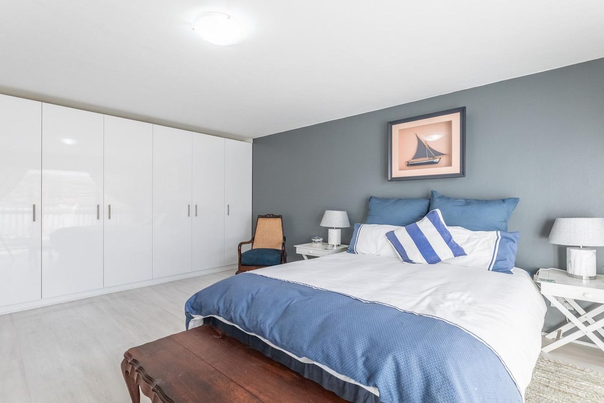 A well-maintained bedroom featuring extensive floor-to-ceiling built-in white cabinetry and a neutral color palette with a feature wall.