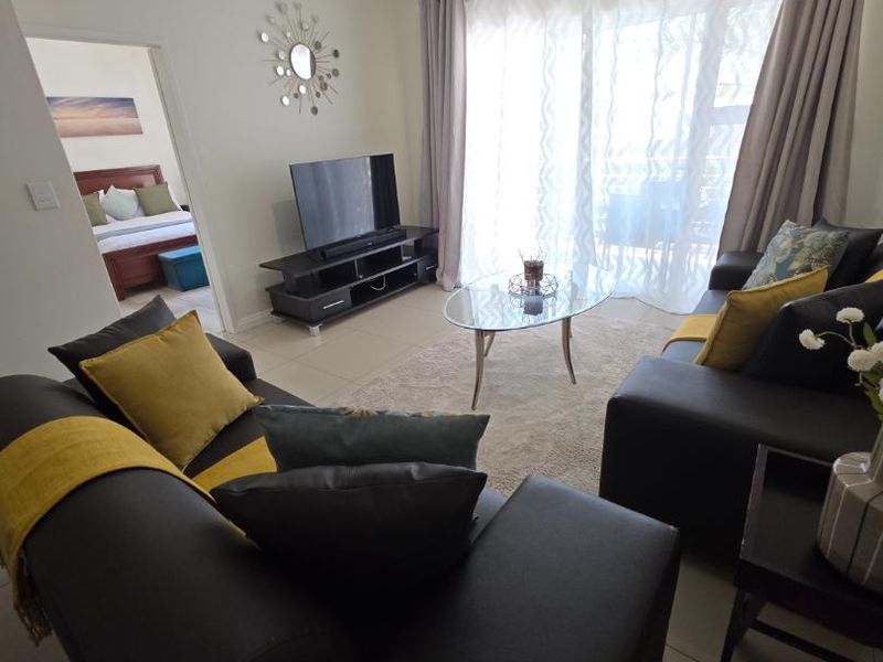 A bright living room featuring tiled flooring and a large sliding glass door that provides access to the outdoor area.