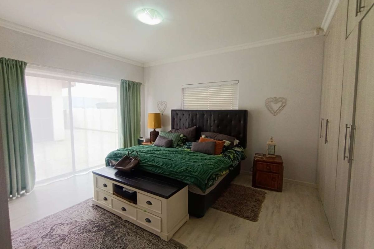 A well-lit bedroom featuring built-in floor-to-ceiling wardrobes, tiled flooring, and sliding glass doors providing access to the exterior.