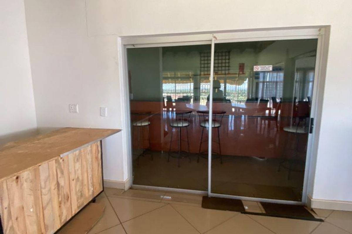 An interior space featuring tiled flooring and a large sliding glass door leading to an outdoor area, currently containing an unfinished wooden counter unit.