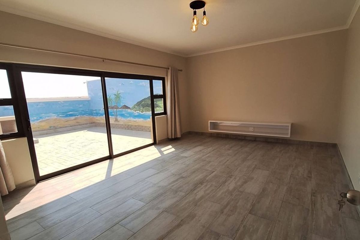 Spacious living room featuring wood-look tile flooring, a floating media console, and large sliding glass doors opening to an outdoor patio area.
