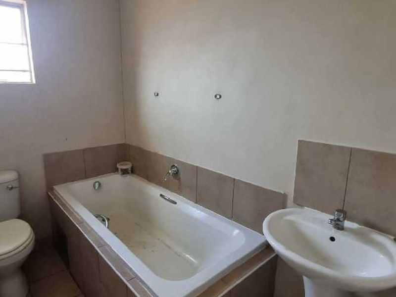 A functional bathroom featuring a bathtub, pedestal basin, and toilet, requiring cosmetic updates to improve its overall condition and appeal.