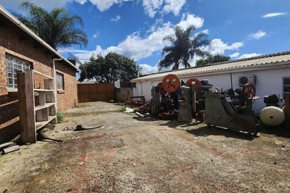 Exterior industrial yard area featuring concrete paving, brick and plastered wall finishes, and space for heavy machinery or equipment storage.