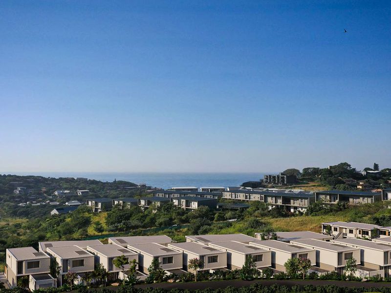 An elevated aerial view of a modern townhouse development situated in a scenic coastal landscape with ocean views.