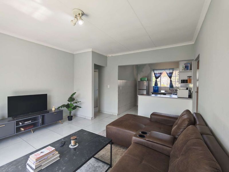 Open-plan living area featuring tiled floors and a connected kitchen with a breakfast counter, offering a functional layout for modern apartment living.
