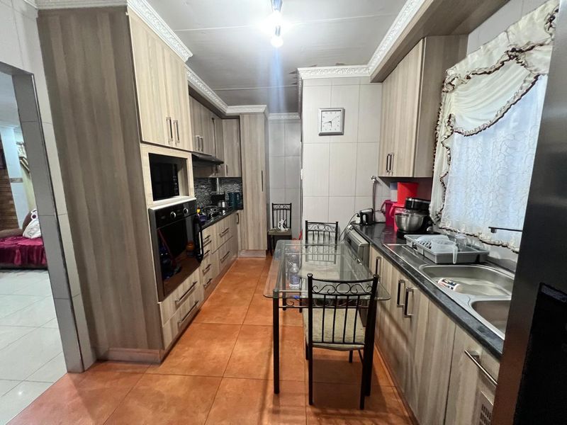 A functional kitchen featuring wood-look cabinetry, built-in appliances, and tiled flooring, requiring some ceiling repairs to restore its overall condition.