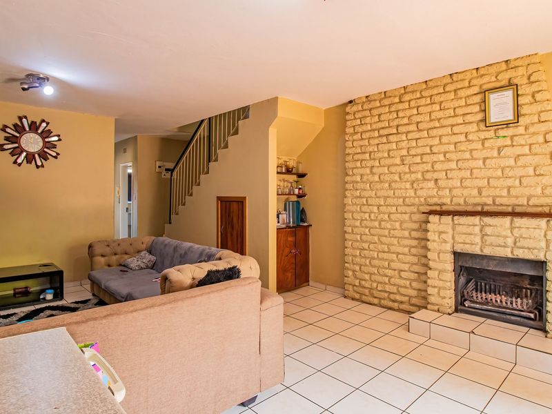 Spacious living room featuring a prominent brick fireplace, tiled flooring, and an integrated staircase leading to the upper level.