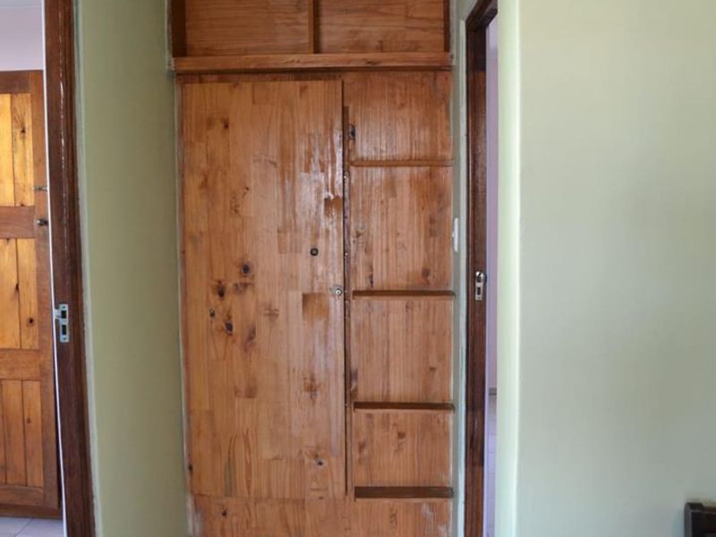 A functional hallway featuring built-in wooden storage cabinetry, tiled flooring, and a classic tongue and groove ceiling with decorative coving.
